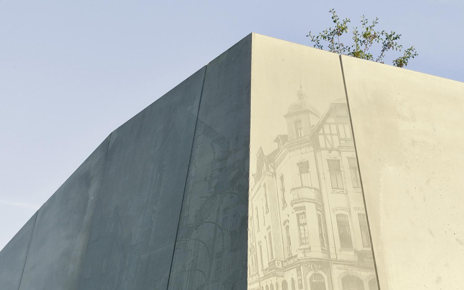 Sichtbetonwand mit Relief historischer Fotografien