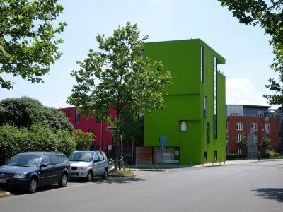Nordwestansicht des leuchtend grünen Turmhauses mit rotem Langhaus im Hintergrund