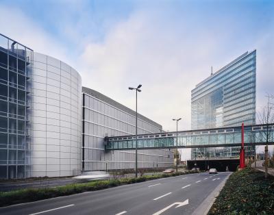 Bürogenäude mit gläserner Verbindungsbrücke, dahinter das Stadttor Düsseldorf
