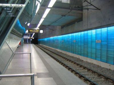 Bahnsteigkante und hinterleuchtete Glaswand