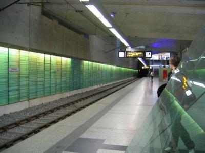Bahnsteigkante und hinterleuchtete Glaswand