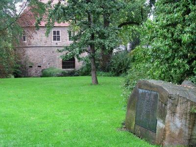 Gedenkstein und Rückseite des Torhauses