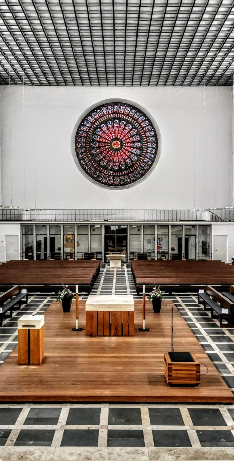 Kircheninnenraum mit Blick über den Altar in Richtung zum großen Rosettenfenster