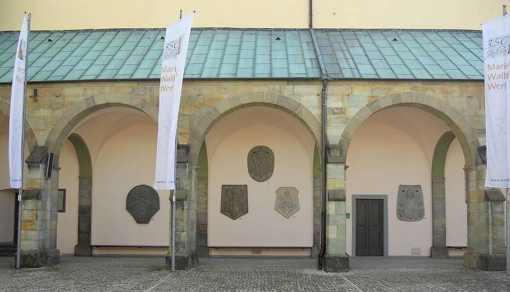 Seitenansicht der alten Wallfahrtskirche mit den Papstwappen
