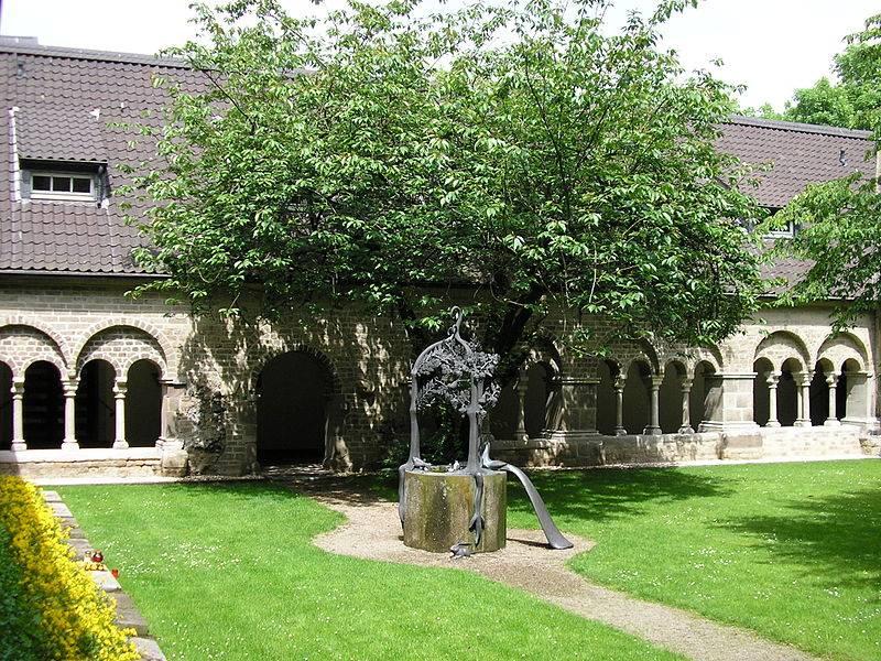Innenhof der Abtei mit Brunnen und Kreuzgang im Hintergrund