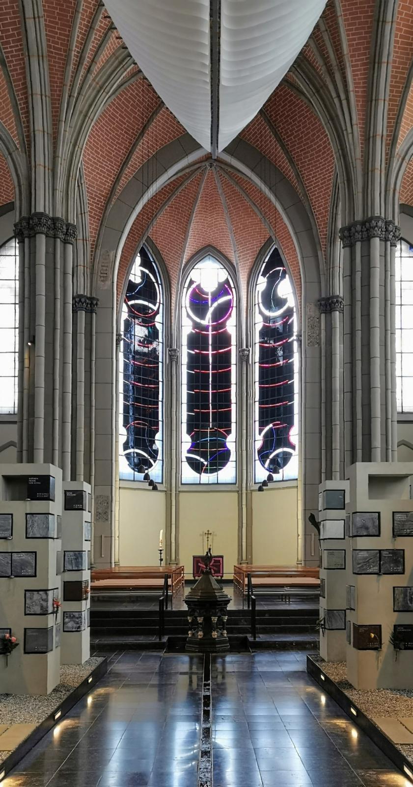 Blick zum Chor mit Wasserlauf und historischem Taufstein